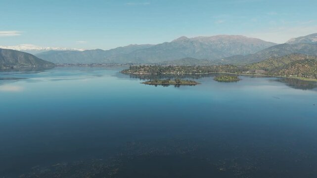 Aerial view of aculeo lagoon reflecting the Andean mountains on a sunny and clear day