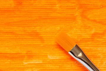 paint brush at striped paper painted with orange gouache