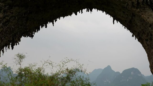 Moon Hill arch with stalactites and mountainous landscape on a cloudy day. Yangshuo, China