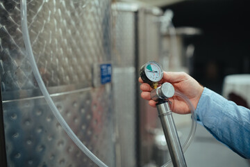Winemaker standing in the wine cellar, controlling pressure in fermentation tank.