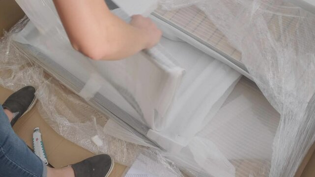 Handheld top shot of unpacking furniture for further assembly. Female hands unpacking furniture.