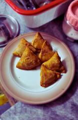 A close-up shot of golden, crispy samosas, perfectly fried and filled with savory spiced ingredients. Their crunchy texture and triangular shape make them a popular, mouthwatering snack in South Asian