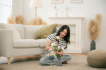 A young girl is arranging flowers in a vase in her living room.