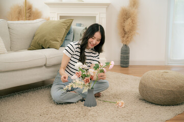 A young girl is arranging flowers in a vase in her living room.