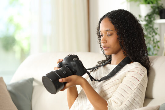 Serious black photographer checking photos on camera at home