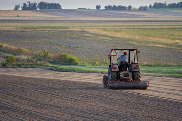 Ploughing a field at sunset with a tractor and plough, ready for crops on a farm © Bagatela