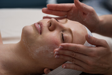 Woman massage and facial spa treatment. Facial treatment of a young female face with serum. Skincare, beauty and wellness clinic. A cosmetologist girl does a facial massage. Cosmetic procedure.