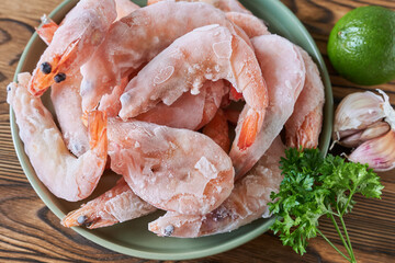 Raw shrimp in a bowl on a wooden table. Top view.