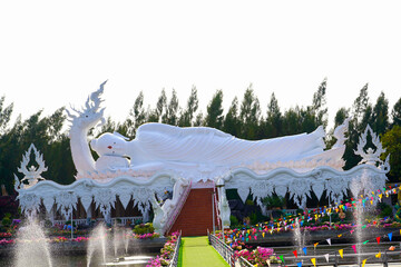 A white reclining Buddha with a dragon on top of his head. The stairs are adorned with dragons spitting out nagas.           