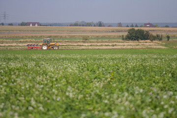 Agriculture machinery in action a tractor plows a field on a bright day