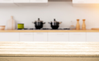 A wooden countertop with a blurred background of a kitchen with pots and pans.