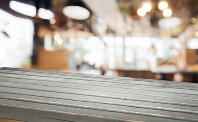 A close-up view of a wooden table top with a blurred background of a cafe interior.