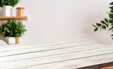 Whitewashed wood table top with a blurred background of plants and a wooden shelf.
