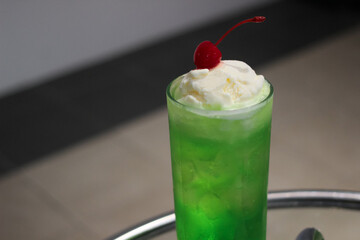 melon soda green beverage and vanilla ice cream and cherry on top