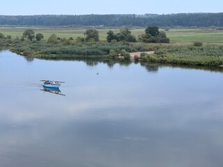 Lonely small boat in the river, shot in the air from hill in Lithuania, quit day