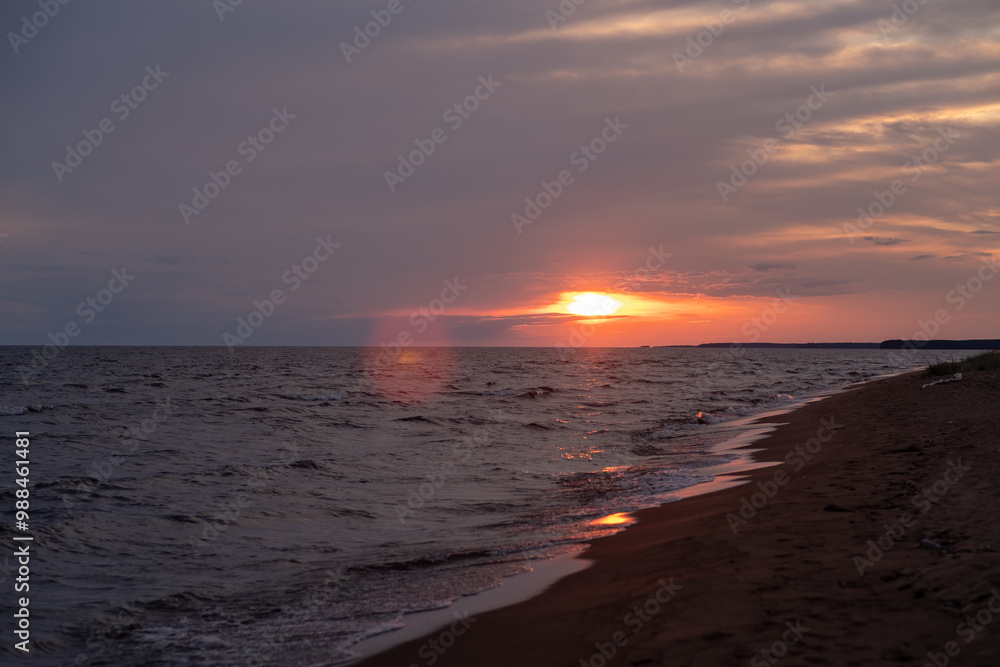 Poster the sun sets gently over the calm water, illuminating the shoreline with soft waves and a vibrant ho