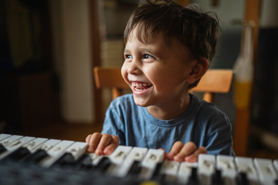Cheerful boy practicing synthesizer at home