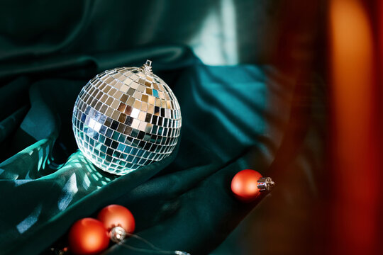 Silver colored disco ball and baubles on green cloth