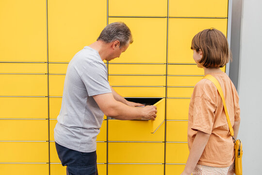 Man removing parcel by daughter standing near locker