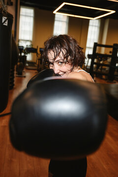 Smiling woman posing with boxing gloves in gym