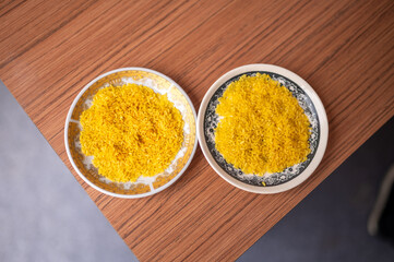 Two plates of vibrant yellow rice placed side by side on a wooden table, showcasing a traditional Indonesian dish.