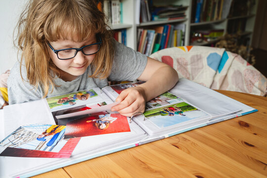 Smiling girl wearing eyeglasses and looking at photographs