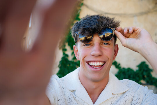 Happy young man with sunglasses taking selfie on sunny day