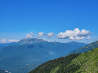 Landscape with high Caucasian mountains in summer with clouds on a bright sunny day