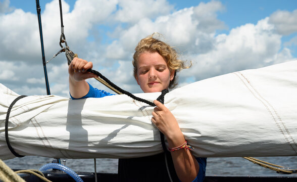 Girl fastening rope on boat in sea