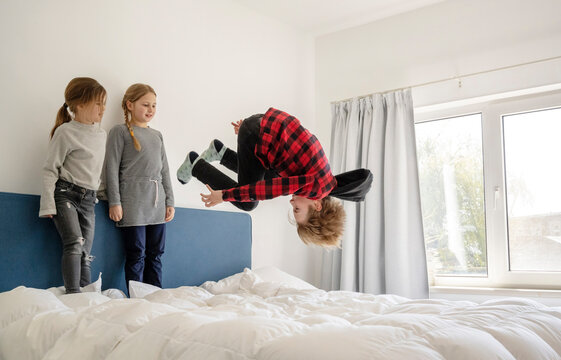 Brother and sisters playing on bed at home