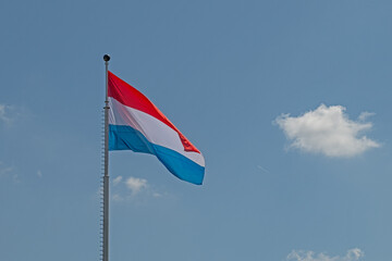 Luxembourg flag on a flagpole in Luxembourg city centre. Blue sky background.