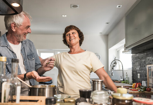 Senior woman complementing man in kitchen at home