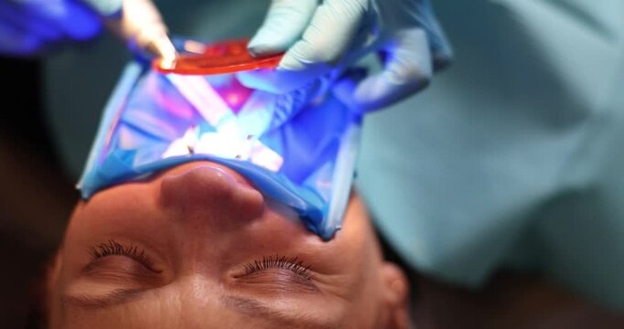 Dentist uses curing light during treatment procedure in private clinic. Medic provides quality services using modern technology in dentistry