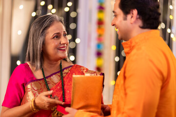 son giving diwali gift to mother at home