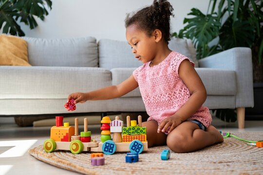 Girl playing toy vehicle near sofa at home