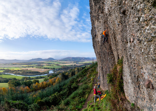 Mature rock climbers climbing rock under cloudy sky