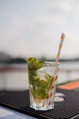 Refreshing Mojito Cocktail with Fresh Mint and Straws on a Sunny Day by the Water