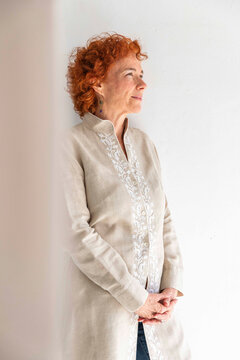 Thoughtful woman standing in front of white wall