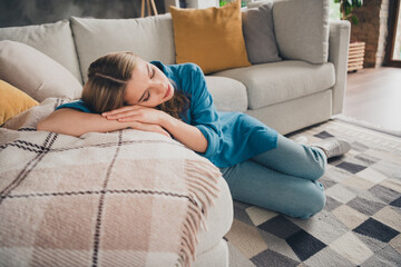 Obraz premium Photo of young attractive blonde hair tired lady laying on sofa sleeping wearing blue casual shirt indoors loft modern design apartment living room