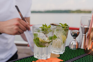 Refreshing Summer Mojito Preparation at a Scenic Riverfront Bar