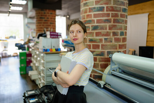 Woman leaning on printer in a printing shop