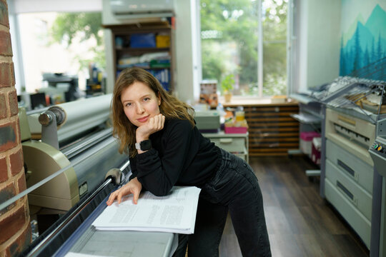 Operator leaning on elbows near large format printer in office
