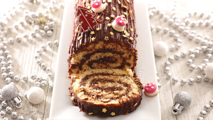 Chocolate Yule Log with Christmas Garland and Baubles – Festive Dessert on Light Background