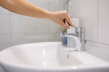 The woman tries to turn on the water in the bathtub, but no water comes out