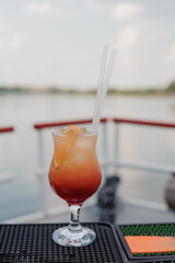 Refreshing Tropical Sunset Cocktail served on a Deck with Scenic Water View