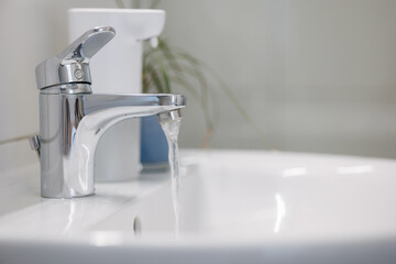A faucet with running water. Water tap made of chrome material.