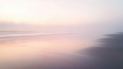 Fototapeta premium A peaceful, foggy beach at sunrise, with smooth wet sand reflecting the soft pastel colors of the sky.