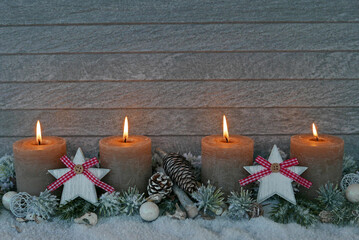 Adventsdekoration: Vier brennende Kerzen zum vierten Advent mit Weihnachtsschmuck und Textfreiraum im Schnee.