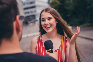 Photo of charming girl giving interview to journalist speaking in microphone broadcast outdoors