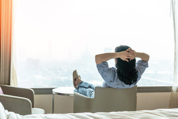 Simple lifestyle take it easy relaxation of Asian businesswoman, healthy woman resting in comfort business hotel or city home living room having lazy free time with peace of mind and work-life balance